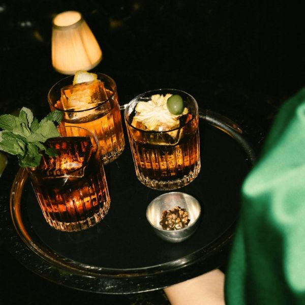 Handcrafted signature cocktails on a round black tray served in a warm ambient lighting at El Baron Saigon