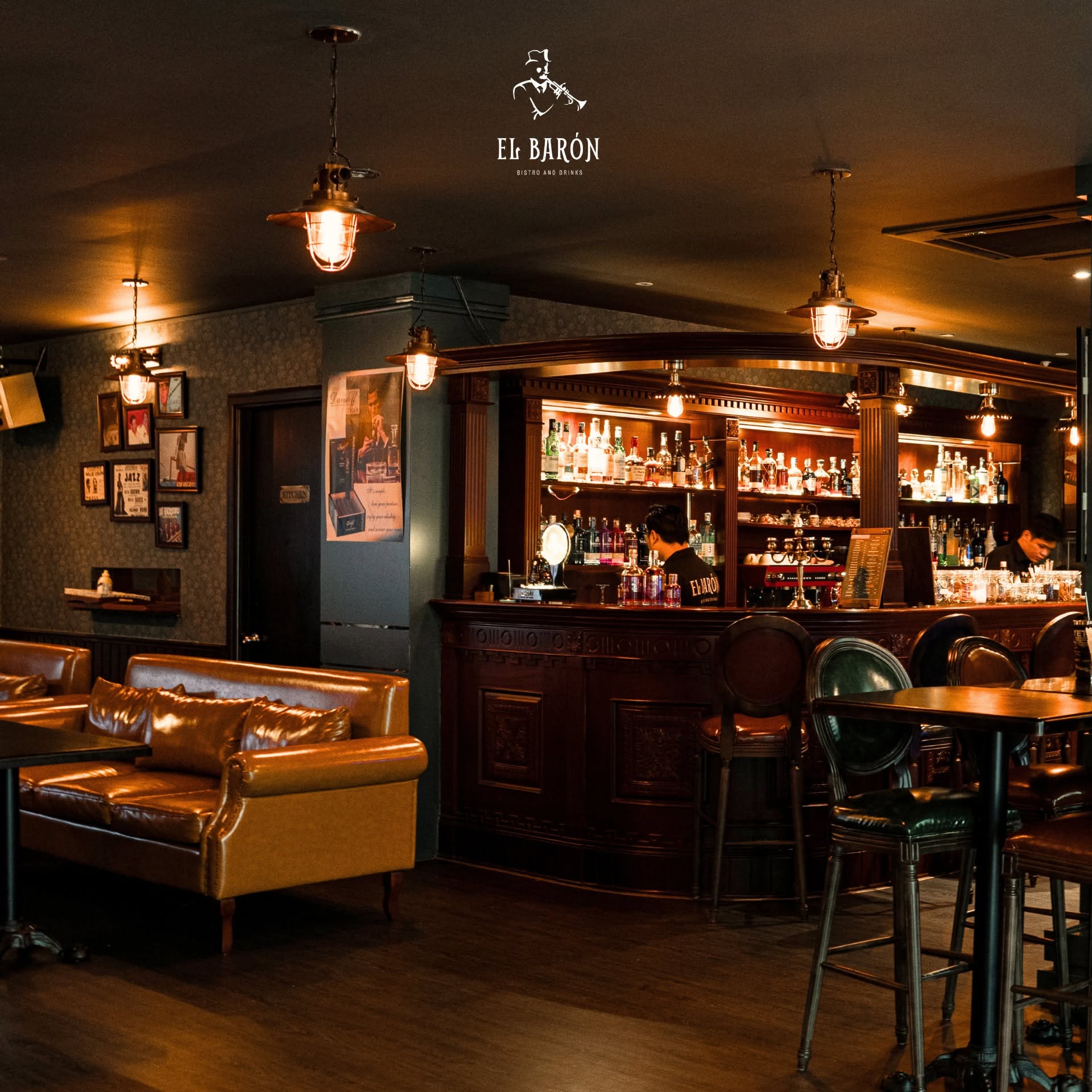 Subtle amber lighting and dark wood bar counter in a District 7 lounge bar setting